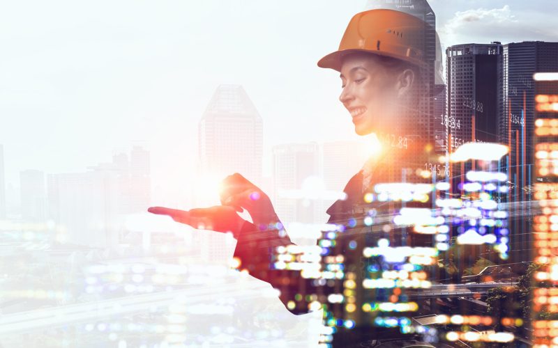 Double exposure of engineer or worker in helmet and modern city background