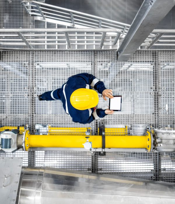 Top view of refinery worker walking by gas pipes, checking gasoline supply and installations in production plant.